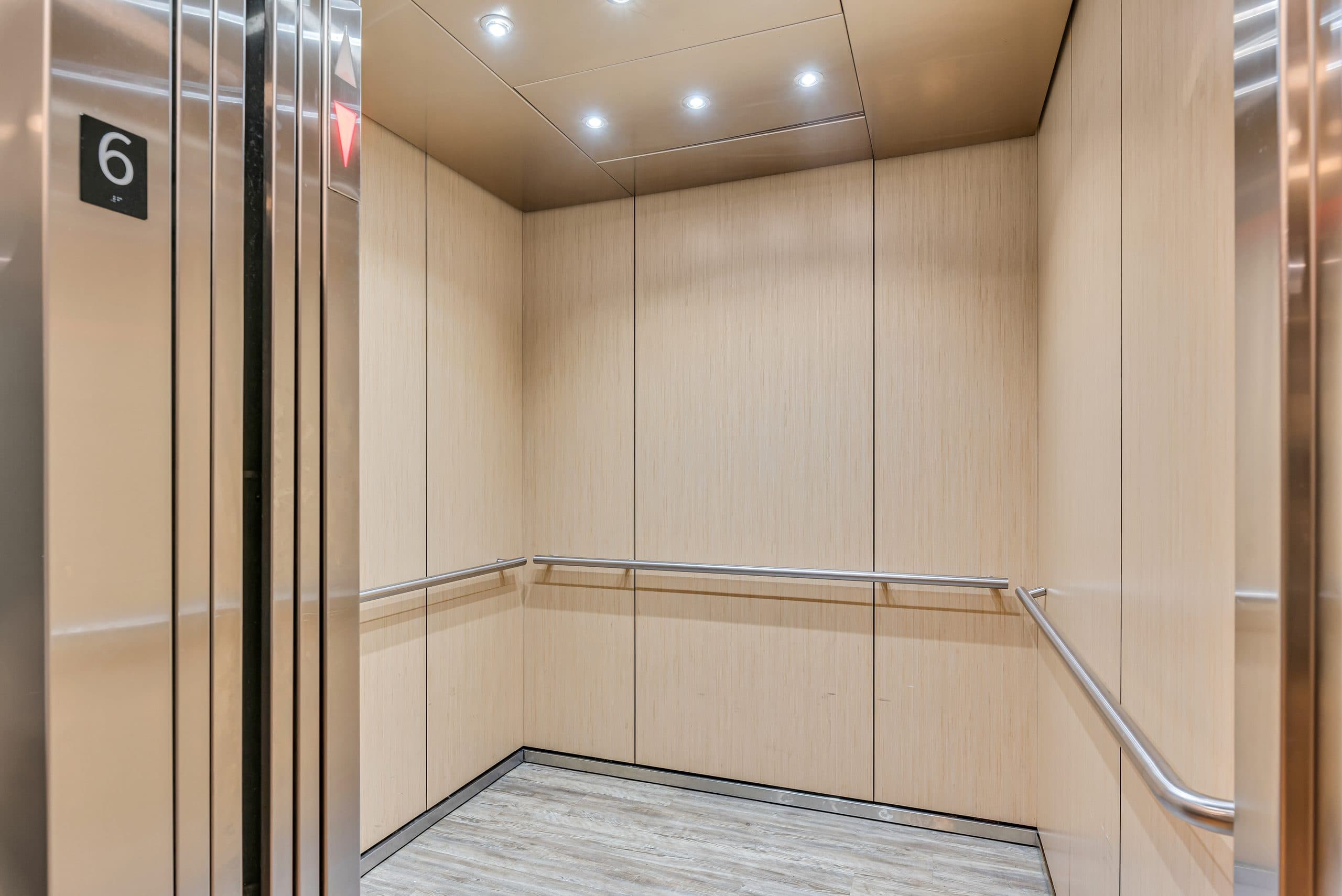 Inside a Columbus Commons elevator cab, finished in pale wood panelling with a stainless handrail