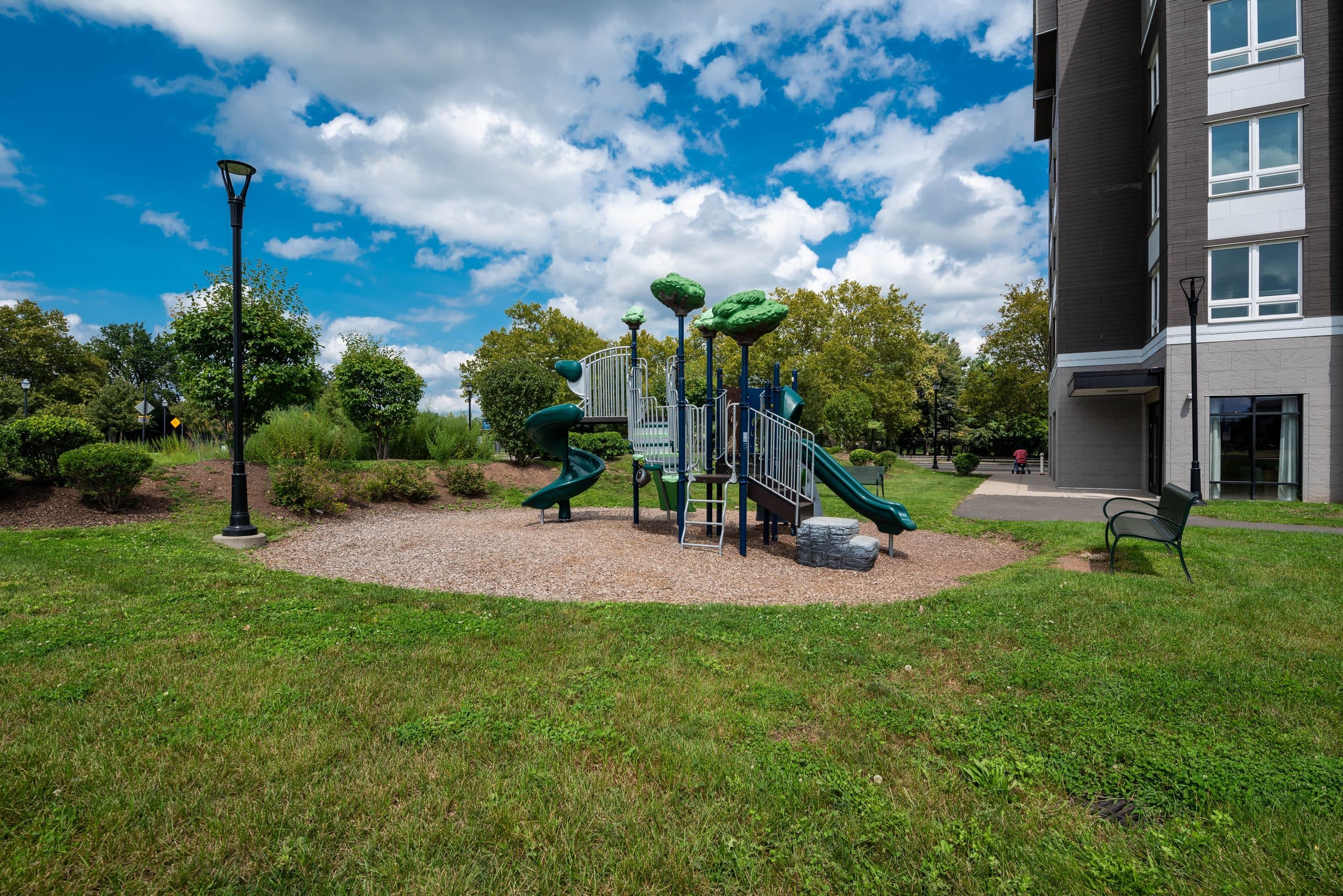 The playground and lawn beside Columbus Commons, with the building rising behind it under a blue summer sky